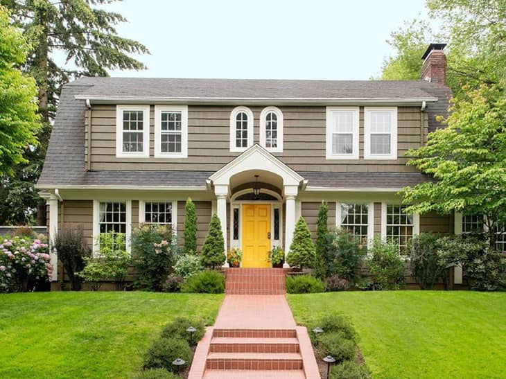 farmhouse exterior in green grey colour with yellow front door and white windows