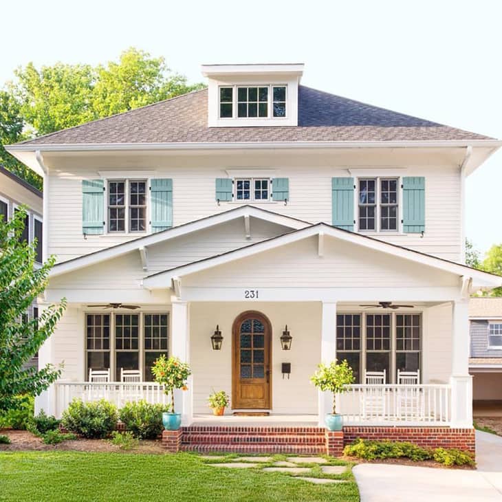 Farmhouse exterior with teal shutters and arched front door