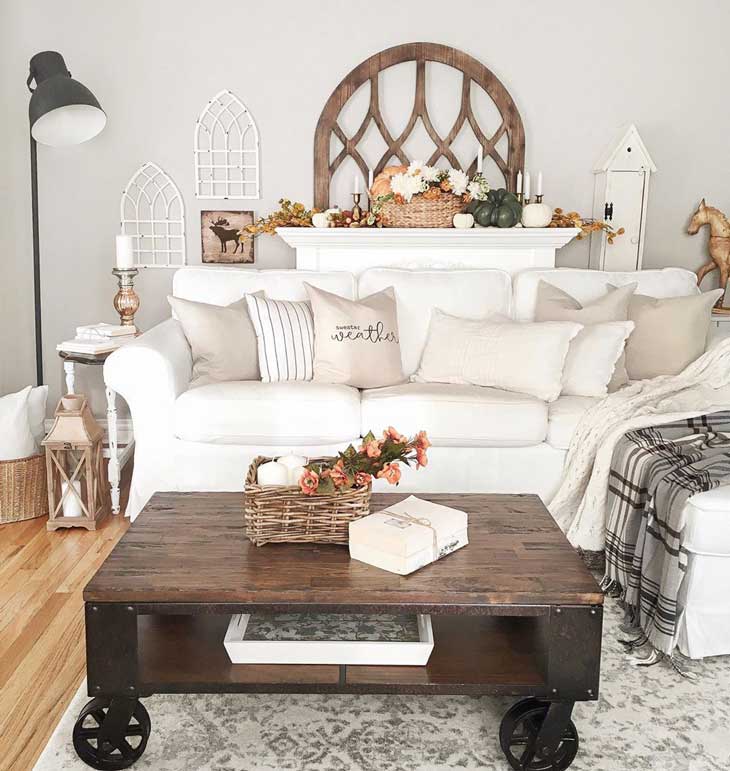 cart farmhouse coffee table in front of a white sectional and rustic window decor on wall