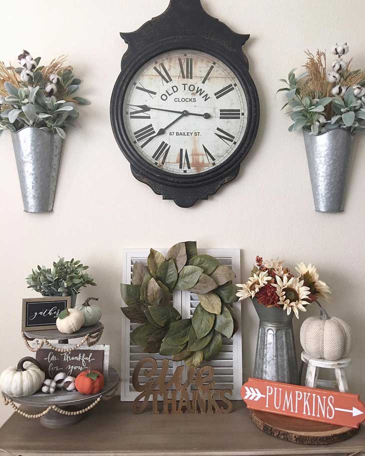 magnolia wreath below rustic clock and metal wall vase