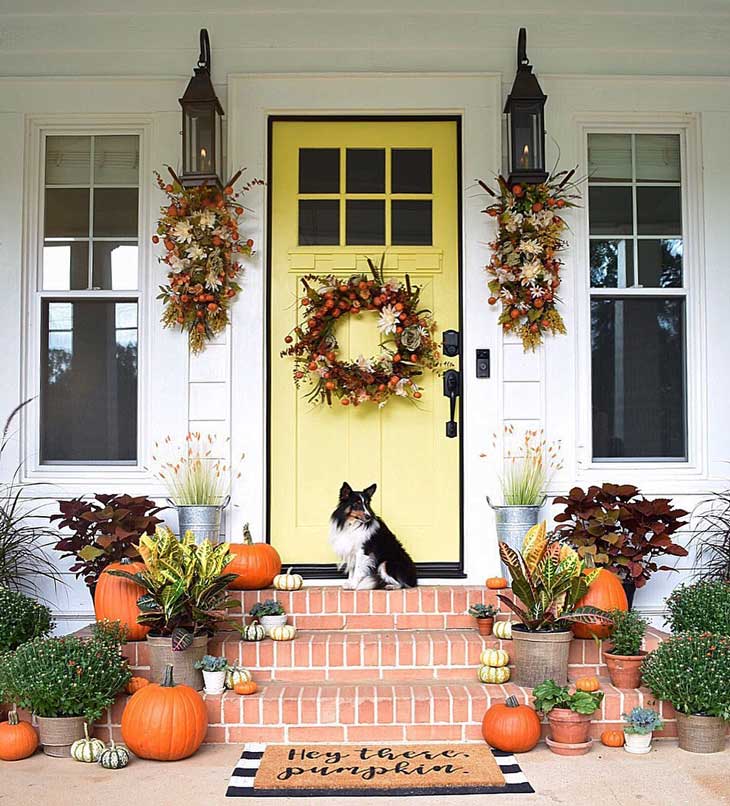 Fall wreath on a yellow front door with pumpkin decor