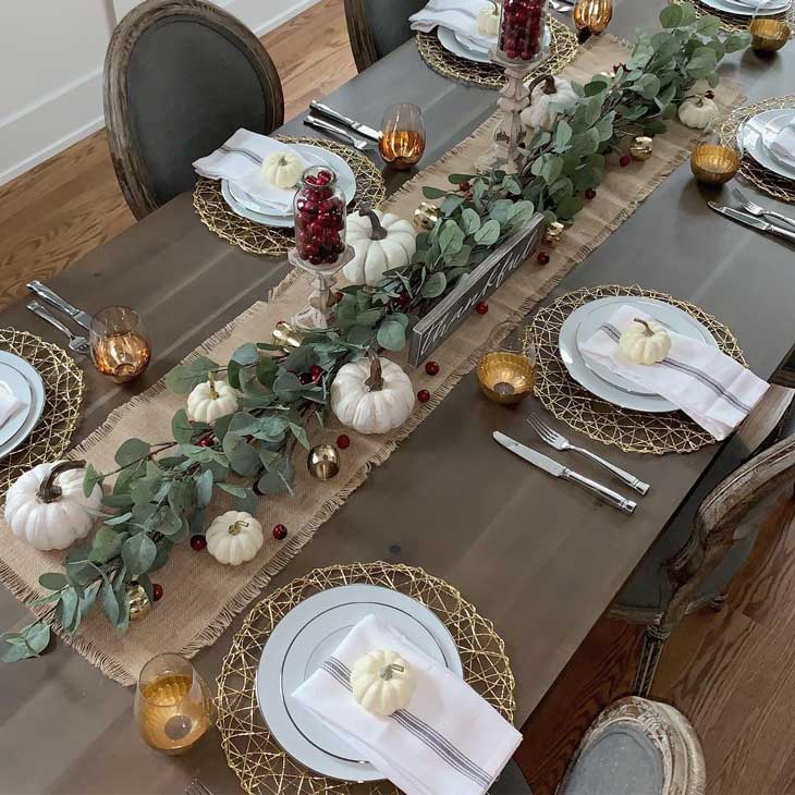 thanksgiving table with green garland and pumpkins