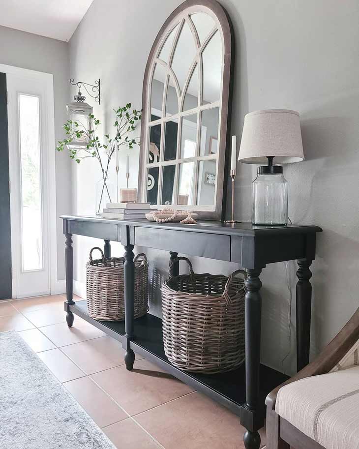 black entryway table decor with arched mirror and baskets