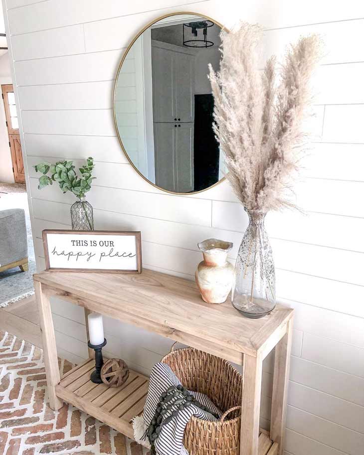 Small entryway table in neutral tone with pampas decor and round mirror above