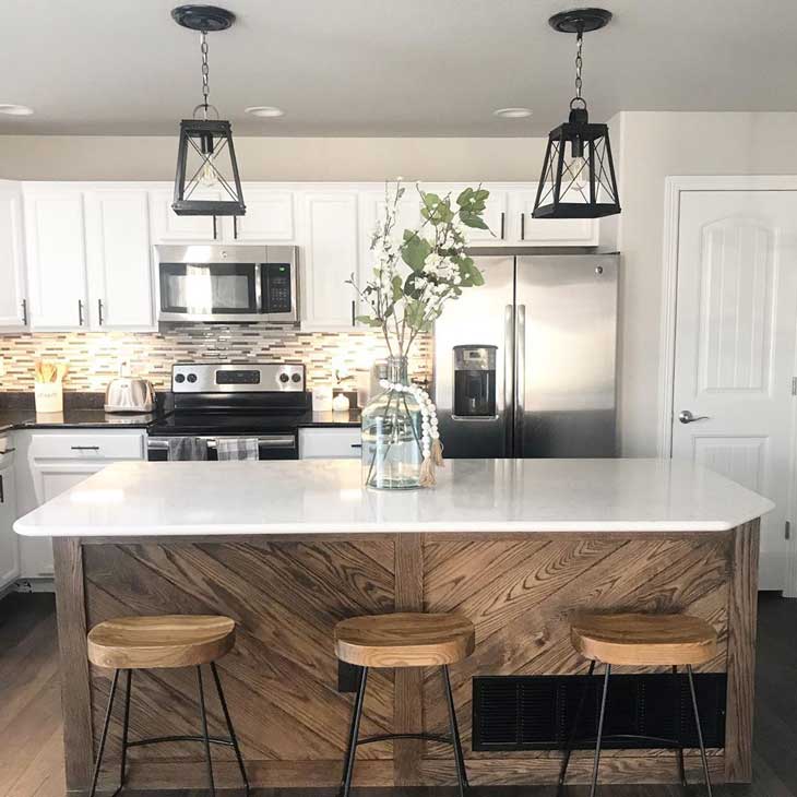 black lantern island lighting over wood kitchen island with white countertop and island centerpiece