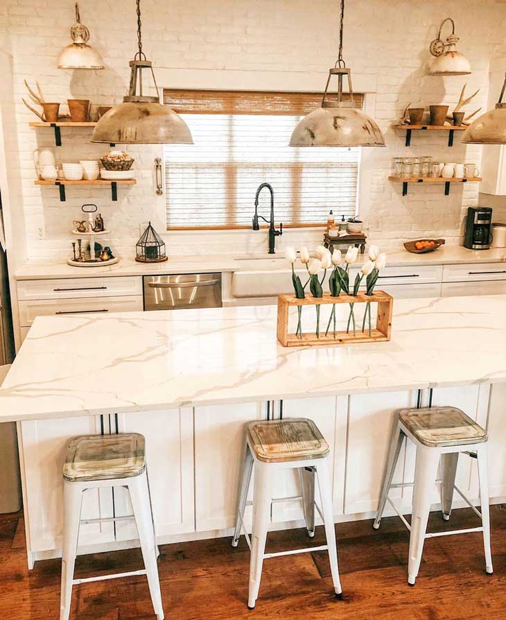 barn-style pendants over white kitchen island with white marble countertop and metal barstools