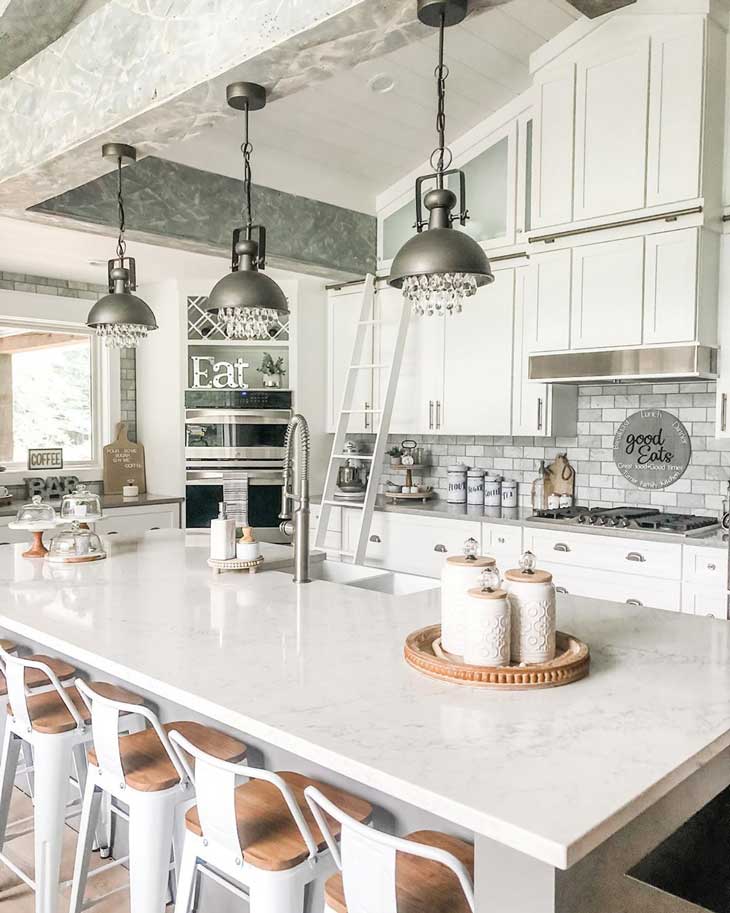 Black industrial pendants over white kitchen island with white marble countertop 