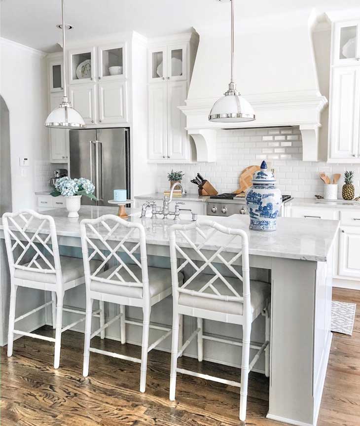 pendant lighting over light grey kitchen island with white bar stools