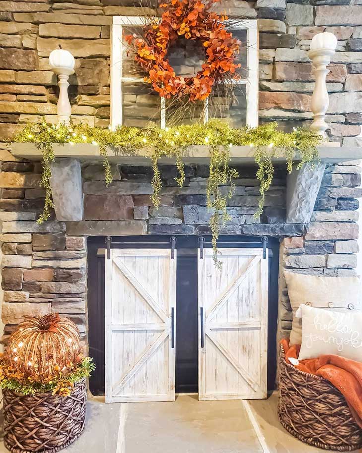 Stone fireplace with fall decor and orange wreath