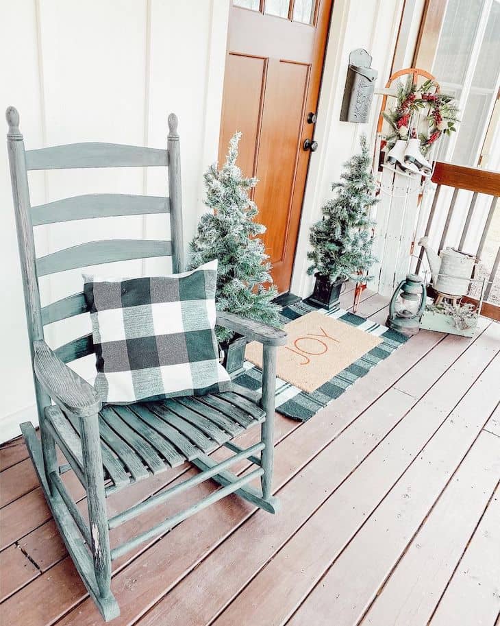 Christmas front porch with small Christmas trees, buffalo check, vintage sled and ice skates.