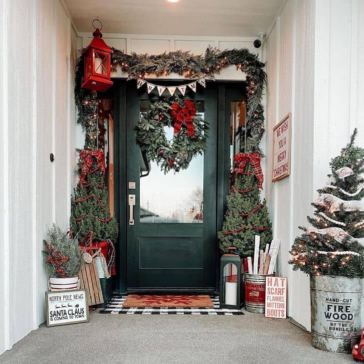 Front porch Christmas decor with cedar garland two trees with red beads and big wreath with red ribbon