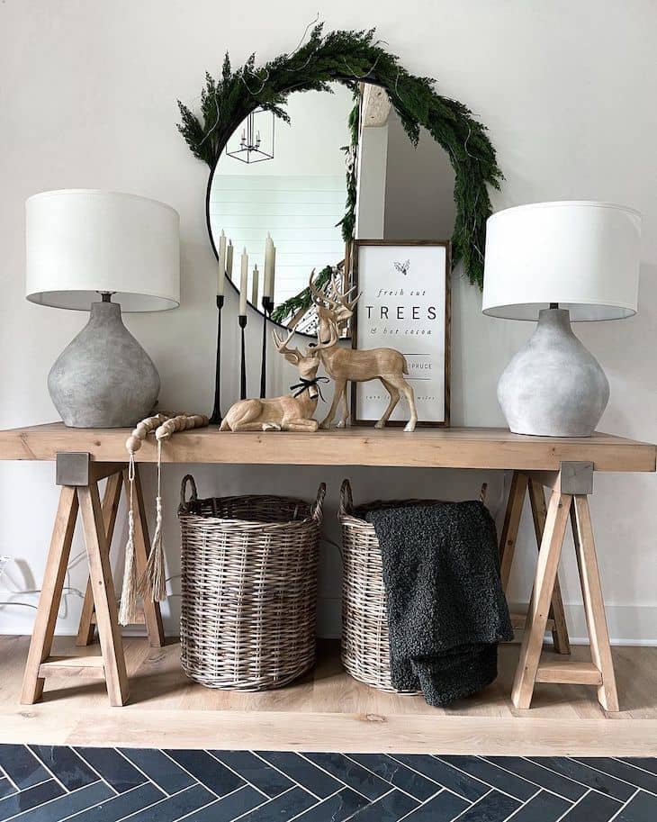 Entryway table with Christmas decor, two table lamps and a round mirror