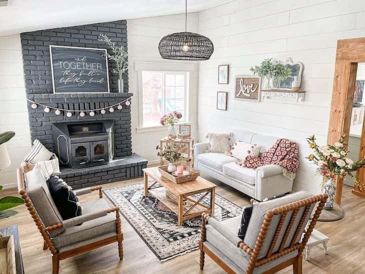 Farmhouse living room with black brick fireplace and shiplap walls in White Dove color