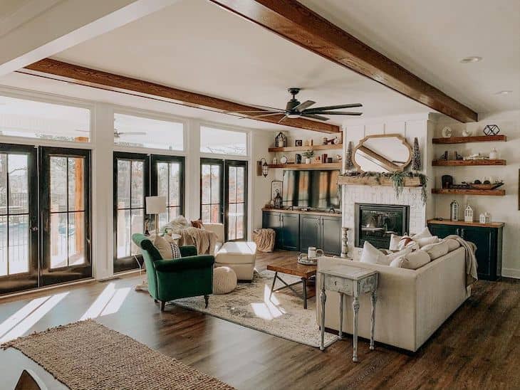 farmhouse living room with wood beams, black french doors, dark hardwood flors and built ins