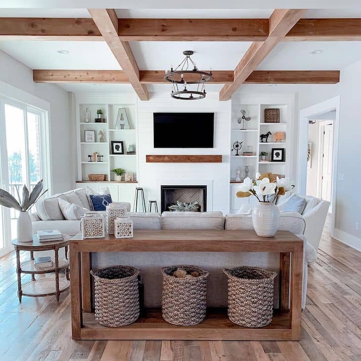 modern farmhouse living room with wood beams, shiplap fireplace, linen couches and wood sofa table