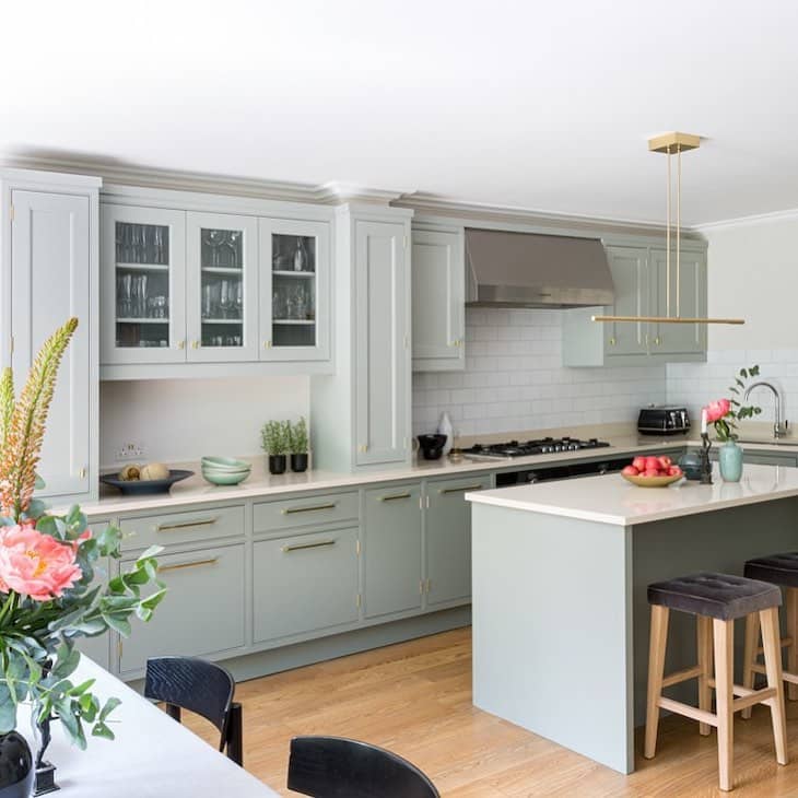 Sage green kitchen with glass upper cabinets and white subway tile backsplash