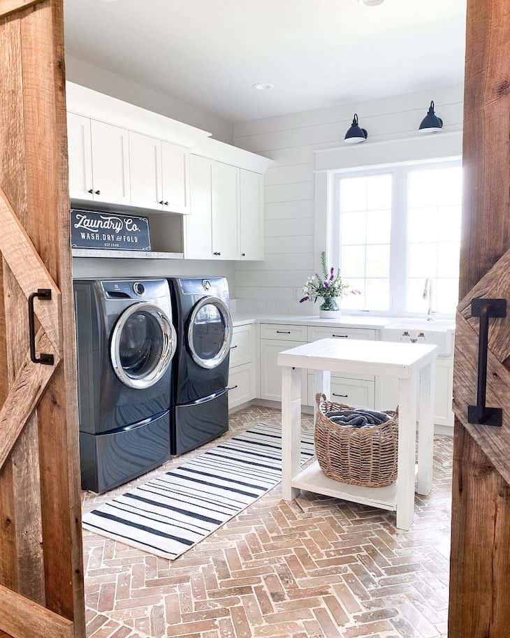 Large laundry room with black washer and dryer and brick floors