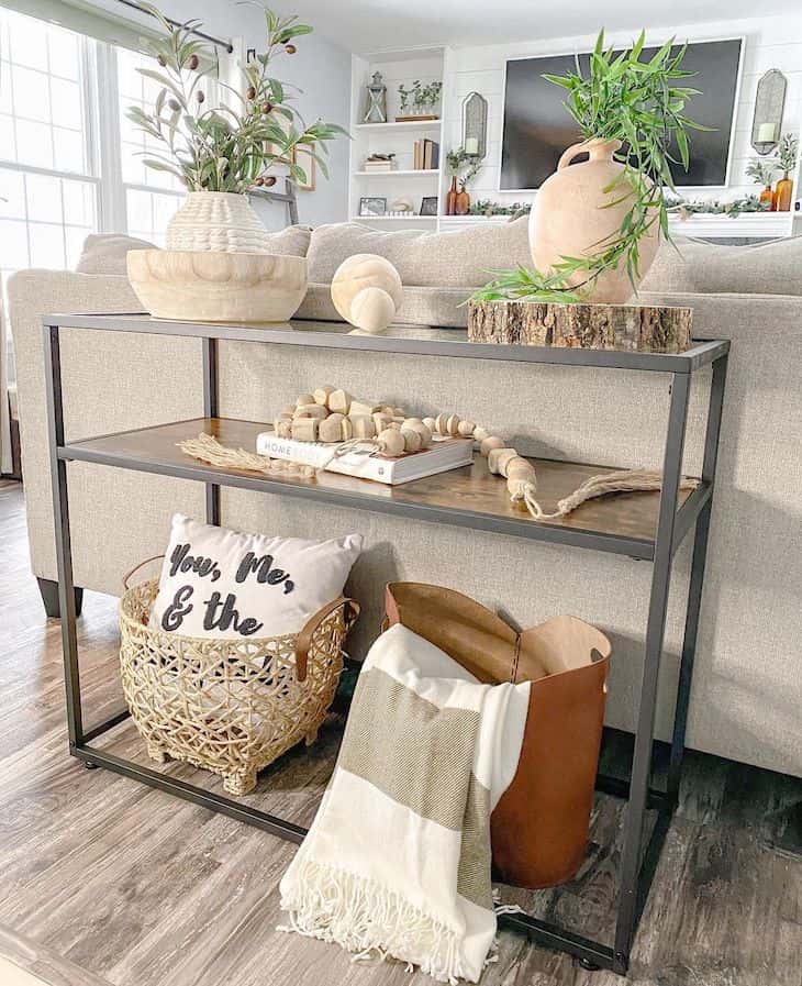 Metal sofa table with glass top decorated with baskets and vases