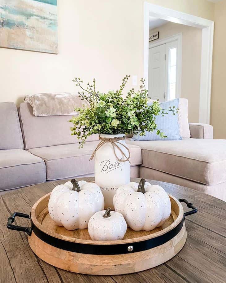 Fall coffee table decor with wooden tray filled with pumpkins and mason jar as vase