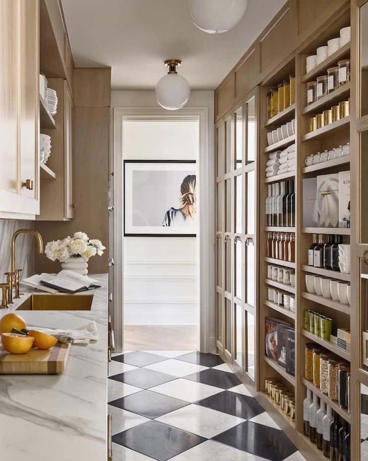 A galley kitchen and pantry with black and white checkerboard floor